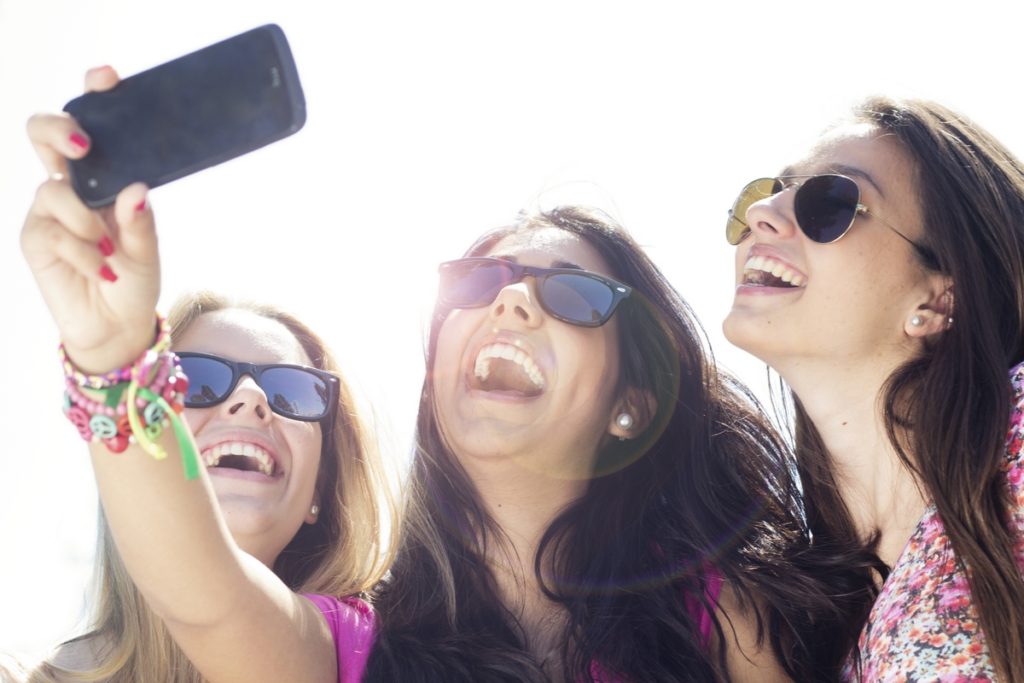 three friends taking photos with a smartphone